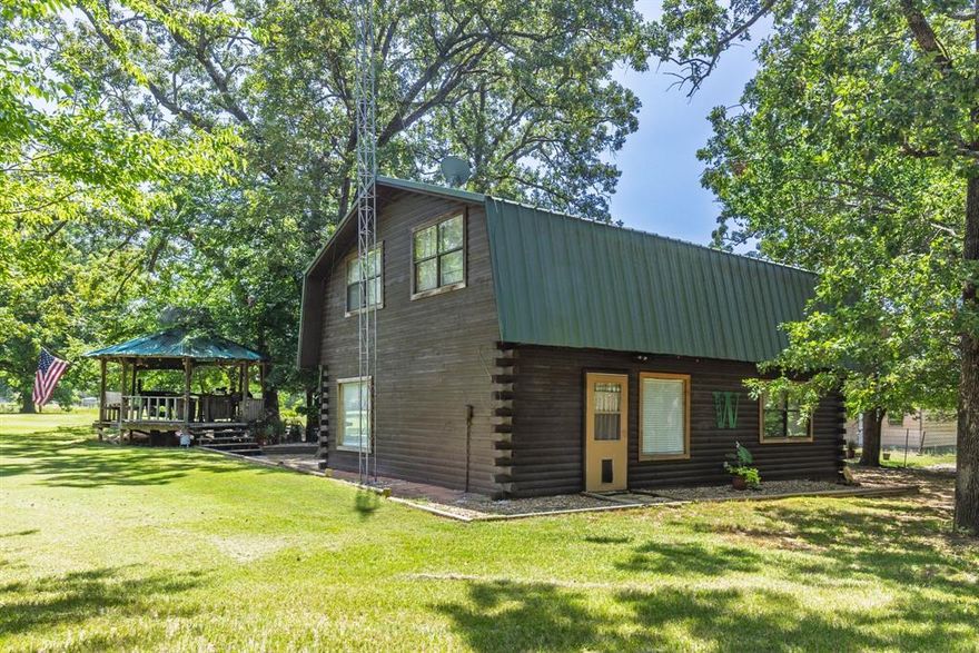 East Texas is calling! Three-Bedroom Log Home with Shop, Pond, and 2+Unrestricted acres.  Well maintained home, Acreage is fully fenced and ready for a range of uses. 2 Producing pecan trees, mature oaks with excellent canopy, Your very own pond with resident ducks. Covered carport with enclosed storage, great for tractor, golf cart or side by side parking. Mechanics workshop, walk through and roll up doors, on slab with electric. Freestanding gazebo equals shaded seating overlooking the pond. Chicken coop area currently home to chickens and a turkey or two, room for other livestock (you could even have baby goats here). Two water meters in place, potential for future use. Home features metal roof, fully electric with central heat and air, extremely efficient. Excellent layout with kitchen open to living, Primary is on main level, upstairs features two good sized bedrooms, full bath and additional family room, office or flex space.  Located oh so close to Lake Fork, within easy reach of Mineola, Emory, and Canton. Private laid-back setting, well suited for those looking to live with fewer restrictions. Fertile soil, space to garden, raise animals, check out the stars! The best part is you are close to amenities, have city water and sewer but still in the heart of nature. Schedule the showing, Start your next chapter, Escape to a new peaceful life.