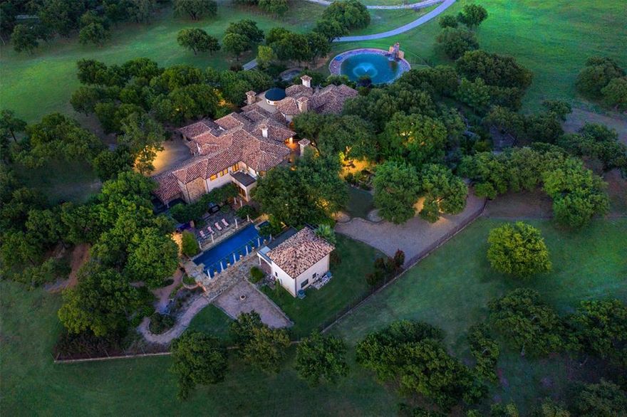 Stepping into Cascina Di Lusso is like walking through the pages of history—where the artistry of the Italian Renaissance converges with the warmth & tranquility of a country setting. Every element of this 11,000+ sq. ft. estate has been carefully curated to honor the architectural mastery of the past while providing an elevated standard of modern luxury. At its heart lies a hand-painted rotunda, an awe-inspiring masterpiece reminiscent of St. Peter’s Basilica, created by renowned artist Gregory Arth. Throughout the home, every material has been selected for its authenticity & enduring beauty. Limestone fireplaces stand as sculptural centerpieces, their hand-carved forms recalling the grand estates of Tuscany. Marble baseboards & hand-carved mahogany details provide a richness that can only be achieved through true artisanal craftsmanship. The walls, finished in the finest Venetian plaster, glow with the depth & texture of centuries-old Italian villas, lending a timeless, lived-in elegance to every space. The soul of Cascina Di Lusso is in the details—imported antique doors from La Puerta, each with a story to tell, frame the home’s archways & corridors, while bespoke finishes by Walker Zanger & Anne Sacks ensure that no element is anything less than extraordinary. The two-story library is an intellectual retreat worthy of Renaissance scholars, while the media room, game room, & 5,000+ bottle wine cellar offers spaces for entertainment & indulgence, seamlessly blending old-world grandeur with contemporary comfort. Beyond the main residence, a 1,320 sq. ft. two-story guest house mirrors the main home’s architectural integrity, providing guests with an equally opulent yet intimate retreat. This estate does not simply borrow from history—it honors it. Every archway, every material, & every carefully selected finish was designed to stand the test of time, ensuring that Cascina Di Lusso remains a timeless work of art for generations to come. 5-21 Acres available.