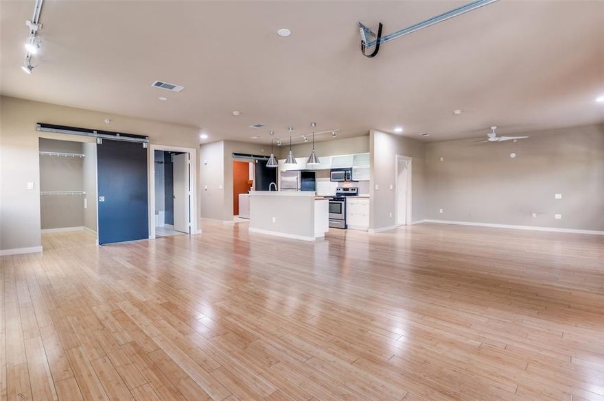 BUZZ LOFTS IS FHA APPROVED. Discover a rare opportunity to own a corner loft condo offering a 2-Bed, 2-Bath OPEN LOFT CONFIGURATION, 1152 sqft of modern urban living, 2 assigned parking spaces (tandem) - complete with INCREDIBLE downtown Dallas views. Located in a gated community in The Cedars, this home places you at the center of a vibrant district known for its energetic nightlife, eclectic art galleries, and immediate proximity to Downtown Dallas. Designed with an urban open-loft aesthetic, this home features modern finishes, high ceilings, and a flexible open layout that adapts easily to your ideal living arrangement. A striking roll-up garage-style door extends the living space onto the wrap-around corner balcony, where views of Akard Street and the Downtown skyline provide the perfect setting for entertaining or relaxing. Bamboo hardwood flooring is located throughout to create a seamless transition for the open floorplan.  The sleek island kitchen is at the center of this space and offers frameless modern white cabinetry, deep storage drawers, butcher block countertops, stainless steel appliances, and a dual-basin stainless sink with high-arc pull-down faucet. The spacious primary bedroom area features an open wood-and-metal dual-sink vanity with a wood countertop, a tub-shower combo with glass sliding doors, white ceramic tile finishes, and a large walk-in closet. The guest bedroom area offers its own walk-in closet with a modern barn-door entry, along with a white vanity, oversized porcelain sink, and white ceramic tile finishes. Additional highlights include an oversized utility room with full-size side-by-side connections that is closed off by a modern sliding barn door. This Buzz Lofts offers an urban lifestyle with an elevator, rainwater harvesting system, secure bike and storage area, and unmatched walkability to restaurants, shops, major highways, the DART Line, and all the culture of the Cedars District - just moments from Downtown Dallas.