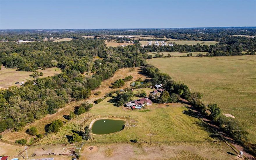 Welcome Home to your Country Retreat ready for Farming and Rural Living! Step into the serenity of this nearly 5 Ag-Exempt acres in Hopkins County, which offers an exceptional opportunity for those seeking a tranquil rural lifestyle or aspiring to embark on hobby farming. Located just west of Winnsboro, along a peaceful country road within the esteemed Como-Pickton ISD, this residence harmoniously combines comfort, functionality, and rustic sophistication. The grounds are fully fenced and cross fenced, accommodating  for a variety of livestock options. There is a substantial workshop with electricity, a barn, multiple outbuildings, dog kennel, and chicken coop providing ample infrastructure for agricultural pursuits. You can enjoy serene afternoons fishing in the stocked pond or relaxing in the above-ground saltwater pool offering the perfect atmosphere for family gatherings or leisure. This three-bedroom, two-bathroom home is a split bedroom layout and enhanced with updates including a recently installed HVAC system, new roof, and an in-ground storm shelter, ensuring comfort and security. Additional amenities include an attached carport, asphalt driveway, security gate, and two covered patios—perfect spaces to appreciate picturesque country sunsets. The interior features two generous living areas: one appointed with a fireplace insert for warm ambiance, and the other with a wood-burning stove ideal for family activities or entertainment. The spacious kitchen and dining area are well-suited for hosting, while an oversized utility room provides extensive storage and workspace, catering to practical needs. It is situated in close proximity to historic Winnsboro with essential services such as medical facilities and grocery stores. This home blends rustic charm with modern comfort, offering an ideal haven for families, hobby farmers, or anyone seeking a slower pace of life. Come see it today to appreciate all the delight this country estate has to offer!
