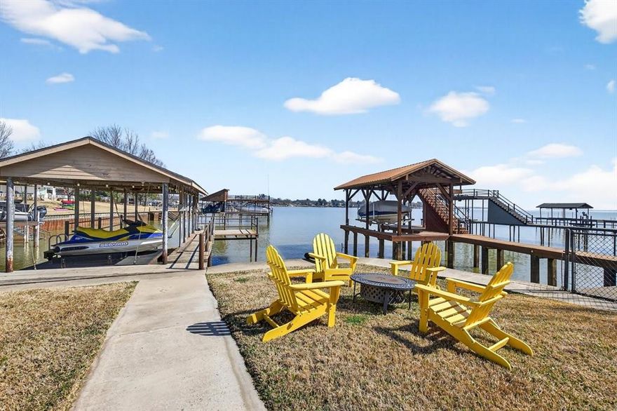 Escape to your own lakefront paradise just an hour from the DFW Metroplex and Tyler. This beautifully updated 3-bedroom, 2-bath home sits along the opening of a canal on Cedar Creek Lake, offering stunning water views and endless outdoor recreation right at your doorstep. The inviting living room seamlessly flows into a fully updated kitchen featuring sleek modern appliances, ample cabinetry, and great counter space — perfect for easy entertaining. Large sliding glass doors frame picturesque sunsets over the water and open to an expansive deck, ideal for outdoor dining or relaxing with friends and family. Step down across the lush, irrigated lawn to your private covered boat dock, complete with boat and double jet ski lifts and convenient steps into the lake. The steel retaining wall and new irrigation system keep the yard looking pristine, while the circular and extended driveway provides plenty of room for guests, RVs, or boat parking. The primary bedroom includes a flexible area ideal for a home office, reading nook, or quiet retreat. Enjoy peace of mind with updates such as windows and sliding doors, foam attic insulation, French drains, smart thermostat, and even included jet ski and trailer — ensuring modern comfort and fun from day one. This property allows short-term rentals, offering excellent income potential for investors or those seeking a versatile vacation getaway. All information deemed reliable. Buyer and buyer agent to verify.