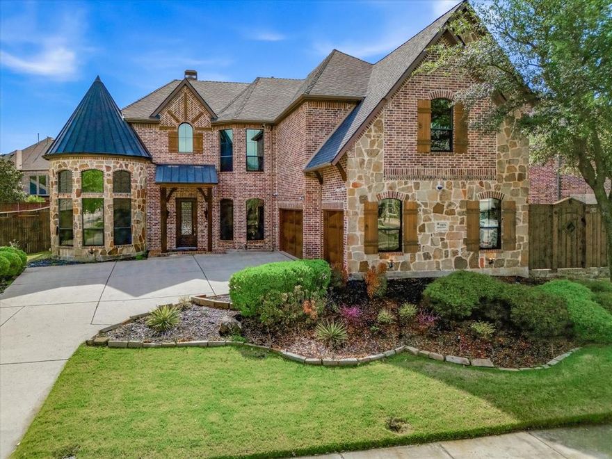 Former model home in Frisco’s Shaddock Creek Estates, this exquisitely appointed residence blends timeless sophistication with thoughtfully curated design and exceptional craftsmanship throughout. Ideally situated near the entrance of the community, the home makes an immediate impression with soaring ceilings, rich hand-scraped hardwood floors, and a grand open-concept layout designed for both refined entertaining and comfortable everyday living. The main living and dining areas are anchored by a dramatic floor-to-ceiling stone fireplace, creating a striking architectural centerpiece and an inviting sense of warmth. The kitchen is a true showpiece, beautifully outfitted with top-tier stainless steel appliances, custom cabinetry, and an expansive island that serves as both a functional workspace and an elegant gathering space. With versatility and comfort at the forefront, the main level features two luxurious primary suites, each designed as a private retreat with spa-inspired en-suites, oversized walk-in closets, and dual dressing areas. A private study offers a polished and peaceful work-from-home setting. Upstairs, the home continues to impress with a spacious game room, an inviting media room with wet bar, and three oversized bedrooms, each offering a sense of privacy and comfort for guests or daily living. Outdoors, the backyard has been transformed into a private resort-inspired escape. The pool showcases a beach entry, waterfall, and spa, creating a beautiful setting for both relaxation and entertaining. A covered outdoor living area extends the home’s entertaining capabilities year-round and is complemented by a custom outdoor kitchen featuring a Green Egg, smoker, and built-in grill. Lush professional landscaping and a newly installed cedar board-on-board fence with hand-dipped, custom-installed pickets add beauty, privacy, and a finished sense of luxury to the grounds.