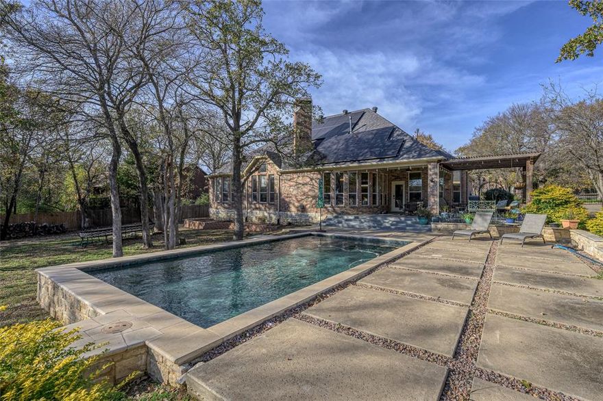Set in a vibrant, family friendly community of upscale homes along the shores of Lake Lewisville, this elegant home sits in a quiet cul-de-sac surrounded by majestic oak trees that provide privacy and a tranquil park-like view.  This custom home has a one-acre fenced back yard complete with an in-ground salt water pool, a cabana-flex space and extension decking adjacent to Corps land and lake access.   The covered back patio and pergola provide the perfect setting for outdoor dining and relaxing after a long day.  Inside you will find vaulted tray ceilings, ornamental molding and baseboards, beautiful tile and wood floors and rooms flooded with natural light. 2 living areas provide flexibility with the larger area adjacent to the kitchen replete with a wood burning stone fireplace. The open floor plan provides a seamless transition between rooms and readily lends itself to entertaining and family gatherings.  The kitchen has plenty of storage and counter space for the most demanding chef with dark counter tops and a dazzling back splash complimented by black and stainless steel appliances.  Enjoy intimate family breakfasts in the adjoining nook while absorbing the morning sun and serene view. 4 bedrooms and 3 full bathrooms complete the home and ensure comfortable family and guest accommodation. The primary bathroom is spa-like with double vanities, a large, jetted tub and a separate shower. The arched openings and custom touches throughout the home contribute to the estate-like ambience and act as a showcase for your personal treasures and touch.  Outside, there is still plenty of space remaining to build a workshop or guest house to complete your vision of the perfect private estate if desired.  An added bonus - no town taxes.  Descriptions don't do it justice - call for an appointment today! All disclosures, survey, HOA By-laws and CCR's are available in Transaction Desk.