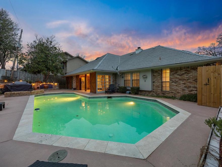 RECENT PRICE REDUCTION!! Experience the best of lakeside living just minutes from Lake Arlington! Nestled in the coveted Shorewood Estates neighborhood, this single-story gem offers a rare blend of character, space, and resort-style comfort. Enjoy a backyard retreat complete with a sparkling in-ground pool, covered patio, and multiple areas to lounge—perfect for entertaining or relaxing after a day at the lake. Inside, you’ll find warm, wood-look tile floors throughout and thoughtfully updated spaces. The remodeled primary suite boasts a stunning steam shower with floor-to-ceiling tile, modern barn doors, and a bright, spacious double vanity, as well as a thoughtfully placed stained-glass window in the primary closet. The open-concept living area is anchored by a whitewashed brick fireplace and rich wood beam mantle, flowing into a light-filled dining room with a wall of windows. The updated kitchen features granite countertops, an island with storage, double ovens, a farmhouse sink, and stainless-steel appliances. Bonus flex spaces include built-in shelves and backyard access—ideal for a home office, playroom, or media space. Additional highlights include ample storage throughout, charming details like shiplap walls, a beautifully crafted custom sink from France in the hallway bathroom, plantation shutters, and a roomy layout with great natural light. Exterior features include a 10' deep pool and a 50-year synthetic slate shingle roof. Residents enjoy close access to the lake, a fishing pier, picnic areas, and nearby Richard Simpson Park. Just minutes from local dining, shopping, and entertainment, with easy access to I-20 and Downtown Fort Worth. Don't miss your chance to own a private oasis near the water—schedule your showing today!