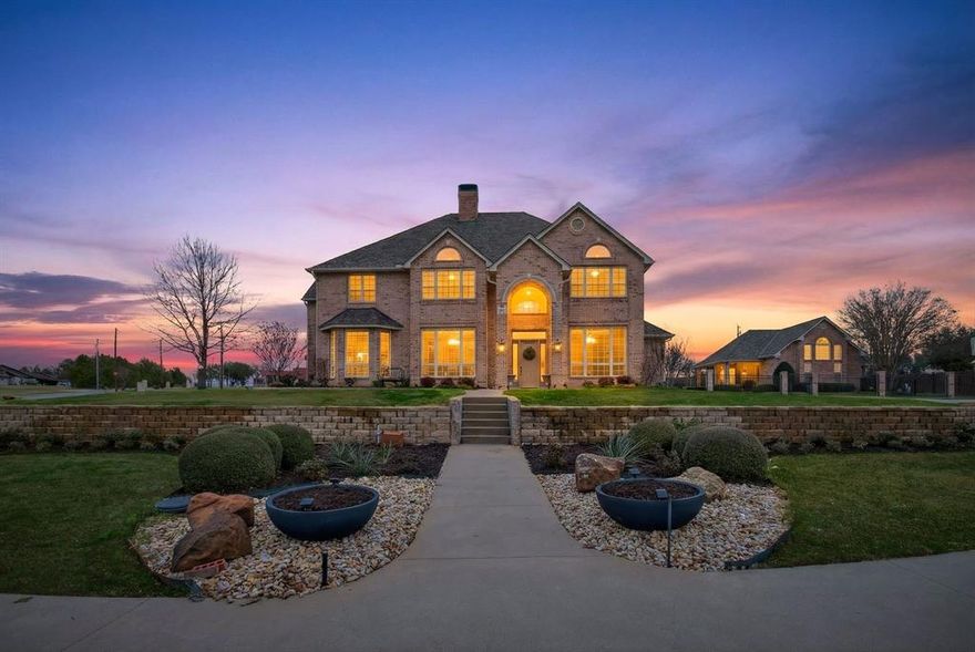 A stunning lakeview estate set on two private acres, offering refined luxury, thoughtful design, and resort-style living in a serene and picturesque setting. This gorgeous property combines elevated finishes with effortless indoor-outdoor flow, creating an atmosphere ideal for both sophisticated entertaining and everyday comfort.

The open-concept interior is anchored by a striking stone fireplace and enhanced by plantation shutters and expansive windows that capture peaceful water views and natural light throughout. The chef’s kitchen is beautifully appointed with an oversized built-in KitchenAid refrigerator, appliance cabinet with interior outlets, wet bar, and an impressive walk-in butler’s pantry designed for seamless hosting.

The primary suite serves as a private sanctuary, featuring a sitting area, direct patio access, spa-inspired bath, and separate his-and-hers walk-in closets. A secondary bedroom downstairs offers ideal accommodations for guests, while upstairs includes three oversized bedrooms with vaulted ceilings, walk-in closets, built-in desks, and an expansive bonus room complete with wet bar and custom cabinetry.
Outdoor living rivals luxury resort amenities with a sparkling saltwater pool, expansive entertaining patios, and a fully equipped outdoor kitchen showcasing premium Coyote appliances, flat iron grill, smoker, refrigerator, sink, and a stunning outdoor fireplace — perfect for year-round gatherings.
The estate also includes an 800 sq ft guest house and an impressive 40x40 fully finished shop featuring spray foam insulation, epoxy floors, and dedicated climate control, offering exceptional flexibility for collectors, hobbies, or workspace needs.
Additional highlights include dual circular drives, side-entry access, and a new Class 4 impact-resistant roof installed in 2025 across the entire property.
A rare opportunity to own a private lakeview retreat where luxury, space, and lifestyle converge.