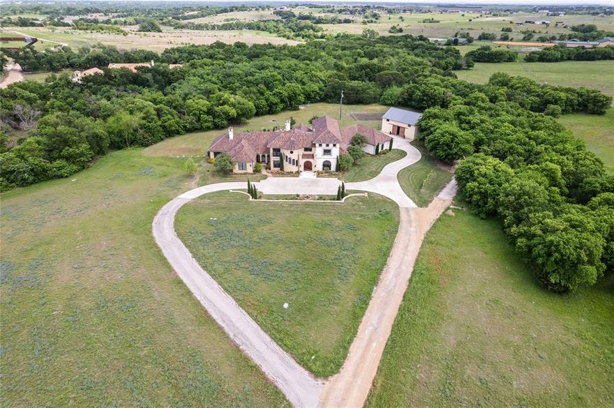 This gorgeous Italian Villa, designed by the renowned Richard Drummond Davis and featured on the cover of Texas Living, is secluded on 18 acres that perfectly blends timeless elegance with modern luxury, bringing the benchmark of Mediterranean style right to the heart of Ellis County! Highlighted by a dramatic entryway, the prominent front turret houses the statement staircase. The foyer opens directly into the expansive family room, dominated by a vaulted ceiling with antique roughhewn wooden beams salvaged from a local barn.  The same rough-faced limestone used on the exterior also define the entry & archways in the living and kitchen.  Entertain effortlessly with a chef's kitchen to die for flowing effortlessly into several dining spaces and living room including both a walk-in pantry and separate butler's pantry.  The primary wing features light gleaming in from windows on 3 sides, a fireplace, French doors providing access to the pool, backyard, covered outdoor kitchen and dining areas.  Few properties can match the design and functionality of the primary bath and 2 primary closets.  Each bedroom has its own ensuite bath AND there's Texas' most relaxing massage room.  Upstairs you'll find the office, guest quarters and the massive media room.  Step outside to your personal oasis; a sparling pool with a one-of-a-kind slide, separate spa, enormous, covered patio with a 3rd fireplace and outdoor kitchen built for hosting unforgettable gatherings 12 months a year.  It doesn't stop there with a detached barn offering extensive storage and versatility easily accommodating 4 more vehicles PLUS your boat, RV and ATV.  This is more than a home- it's private estate where luxury, space and lifestyle come together in perfect harmony.