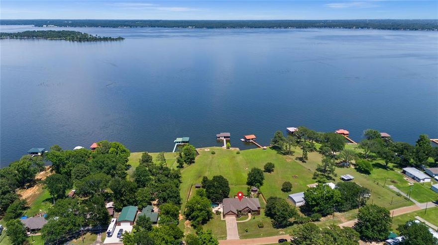 This Lake Palestine gem HAS IT ALL! Your private waterfront oasis awaits! Enjoy stunning open-water views from your own backyard paradise, complete with a brand new gunite pool and hot tub, outdoor kitchen, and expansive patio area, perfect for entertaining or relaxing in style. Swim while overlooking the peaceful lake, or take advantage of the new boathouse, which includes an electric boat lift, dual jet ski lift, and a paddle boat, kayak ramp. A spacious 14x16 open deck and 16x20 covered area provide ample space for lounging and lakeside gatherings, while a 12x12 enclosed room with bar access makes year round entertaining a breeze. Plus, a newly installed bulkhead adds both beauty and functionality to this exceptional property. Inside, the home features a warm and welcoming stone wood burning fireplace in the family room, a formal dining room, office, a cozy breakfast nook, and a breakfast bar for casual meals. The split bedroom floor plan offers privacy and comfort for family and guests alike. Whether you're hosting summer parties, enjoying peaceful sunsets, or boating across Lake Palestine, this home is the total package for lakefront living. Don’t miss your chance to own this incredible waterfront retreat!