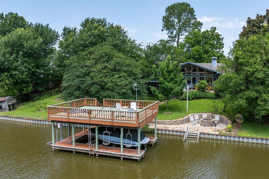 Escape to your own Lake Paradise in this LARGE home on Cedar Creek Lake, made for entertaining family and friends. This 3743 sf home sits on two lots, built from set-back to set-back. Enjoy the cool lake breeze on 160' of shoreline in a large backyard with many places to enjoy. Look over the lake by the fire pit, on the boat dock, or cool off under the huge oak tree by the 3 level koi pond. Boat dock has electric lift (with remote) for boat, and an electric lift for jet ski. Home in a DEEP channel right off the open water, so safe for swimming and bird watching. The home has a large stone deck (no maintenance) with a dining space and covered rest and relax area. Freshly painted, inside and out. The home has a great floor plan with the primary bedroom on one side, and 3 guest rooms on the other end of the house, all with new carpet. The heart of entertaining is a great room with expansive windows, and a game room with pool table and attached bar area. The eye popper of the great room is the circular stone fireplace visible from all the spaces... it lights with a twist of a button with propane and artificial logs. Surround sound equipment and TVs throughout the house will stay. The kitchen is bright and colorful with an granite island that seats up to 6, lots of storage, and 2 refrigerators. The wet bar has a mini refrigerator, sink and divides the great room and dining room. The primary bedroom is a large suite with a fanciful bathroom, with separate shower and tub. French door access to the swim spa on the back trek type deck. Full size utility with washer dryer and deep freeze. Huge multi-use living space at the porte cochere entrance. Separate 593 sf room on the other side of the garage with water and electricity. RV hookups in front. Saloon style outdoor playhouse, and shed. Irrigation system from lake. This home has been in the same family for over 20 years, and it's time to share this lakeside haven with another family. TURN KEY to enjoy this summer!