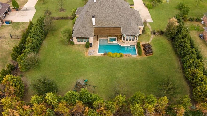 Beautiful custom-built home on over an acre with a private backyard retreat featuring a pool, spa, and covered pergola patio. This 4-bedroom, 3.5-bath home offers quality craftsmanship, spacious living areas, and timeless finishes throughout. The main living area features soaring ceilings with exposed wood beams, rich hardwood floors, and a striking floor-to-ceiling stone fireplace. The chef’s kitchen is designed for entertaining with custom cabinetry, a large island, professional-grade gas range, double ovens, stainless appliances, and abundant counter space. The home offers multiple living spaces including a dedicated study with impressive built-in cabinetry and a bright family room with custom built-ins and large windows overlooking the backyard. The spacious primary suite includes a spa-like bathroom with soaking tub, oversized walk-in shower, dual vanities, and abundant natural light. A large utility room with sink, extensive cabinetry, and island workspace provides exceptional storage and functionality. Step outside to the beautifully landscaped backyard with a resort-style pool and raised spa, water features, and a pergola-covered patio perfect for relaxing or entertaining. Mature trees frame the property and create privacy across the acre-plus lot. The oversized 3-car garage easily accommodates full-size truck and offers additional storage. A rare opportunity to own a thoughtfully designed custom home offering space, privacy, and exceptional indoor-outdoor living.