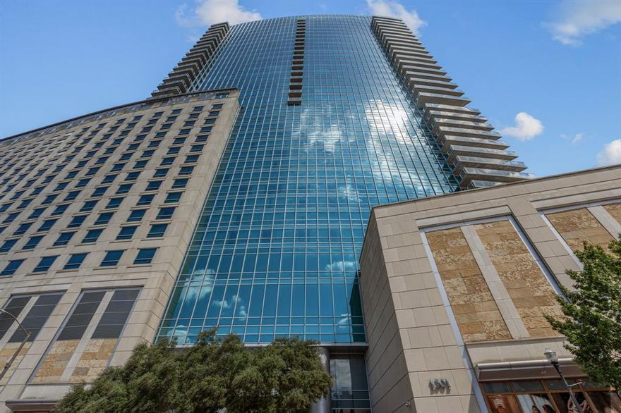 Welcome to Residence 2402 at the Omni, a sophisticated 2-bedroom, 2.5-bath high-rise retreat in the heart of downtown Fort Worth. Floor-to-ceiling windows showcase sweeping skyline views that extend to Dickies Arena, while a wraparound balcony invites effortless indoor-outdoor living. Inside, the open-concept design is anchored by a chef’s kitchen with marble counters, Viking appliances, and seamless flow into the dining and living areas. The primary suite is a private sanctuary with a spa-inspired bath featuring a soaking tub, separate shower, and dual vanities, while the guest suite provides comfort and privacy for family or visitors. A refined powder bath enhances the thoughtful layout. Residents of the Omni enjoy 24-hour concierge service, a resort-style pool, and a state-of-the-art fitness center. Just steps from world-class dining, entertainment, and culture, this residence offers not only a home, but an elevated urban lifestyle defined by luxury and convenience.