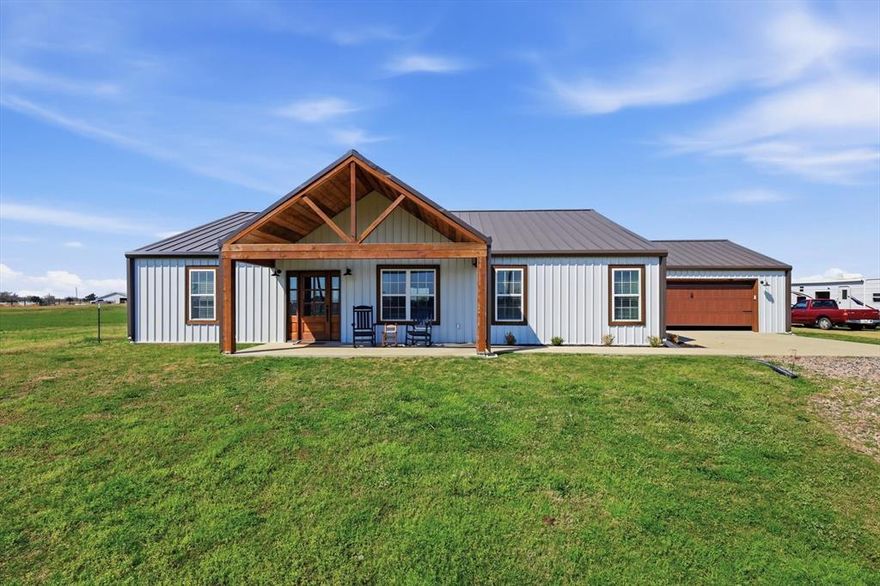 Welcome to this stunning custom-built barndominium, perfectly situated on a peaceful 1-acre lot where thoughtful design meets warm, rustic charm. This beautifully crafted 3-bedroom, 2-bath home is a true testament to the care and attention the owners poured into every detail of its construction. From the moment you step inside, you’re greeted by rich wood accents that create a cozy yet refined atmosphere. Gorgeous wood beams, custom cabinetry, and carefully selected finishes bring character and warmth to every room, blending modern comfort with timeless country style. The open-concept living area is both inviting and functional, designed for gathering, entertaining, and everyday living. The kitchen showcases quality craftsmanship with custom woodwork, ample storage, and a layout that reflects both beauty and practicality. The primary bedroom continues that same level of detail and character, highlighted by striking exposed wood beams that frame the tray ceiling. These beams add dimension, warmth, and architectural interest, transforming the space into a cozy yet refined retreat. Each bedroom offers comfort and space, while the primary suite provides a relaxing retreat with its own private bath. Every inch of this home reflects intentional design—from the layout to the materials—showing the pride the owners took in building something truly special. Outside, the full acre offers endless possibilities, whether you envision outdoor entertaining, a workshop, or simply enjoying the quiet surroundings. This one-of-a-kind barndominium is more than just a home—it’s a thoughtfully designed lifestyle.