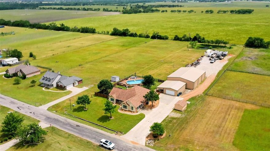 Escape the city and enjoy space, freedom, and fresh air with this beautifully updated home on 2 acres with a pond. Perfect for families, hobbyists, or small business owners, this property offers room to grow and endless possibilities. A 50' x 70' workshop with a finished office and full bath is ideal for a home business, studio, or storage. The property is fully fenced and includes a storm shelter and peaceful pond for added charm and peace of mind. Inside, the 2024 renovation features an open layout filled with natural light, durable wood-look tile floors, and a cozy wood-burning fireplace. The kitchen offers Corian countertops, a walk-in pantry, and a breakfast bar—perfect for family meals or entertaining. The spacious primary suite includes a spa-like ensuite with a soaking tub, walk-in shower, dual vanities, and a large walk-in closet. Enjoy outdoor living with a covered patio, above-ground pool with deck (2023), dog run, and plenty of space for animals or gardening. Additional upgrades include new windows (2023), HVAC (2021), and water heater (2020). This home is the perfect mix of comfort, function, and country lifestyle — all within easy reach of town and Interstate 30. Special financing available — contact us for details!