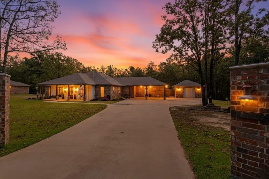 Enjoy the best of both worlds—peaceful country living just minutes from Tyler! This stunning 2.88-acre estate features two Acadian-style homes designed for comfort, convenience, and connection to nature. The 3,160 sq ft main home offers an open floor plan with a chef’s kitchen boasting a massive black walnut island, Taj Mahal quartzite countertops, double ovens, gas cooktop, and commercial-grade fridge and freezer. The living room includes a wood-burning stove and built-ins, plus an all-season sunroom for year-round enjoyment. The private primary suite features an oversized double shower, dual vanities, and large walk-in closet. Two bedrooms share a Jack-and-Jill bath, and the front bedroom is ADA accessible with its own en suite bath. Additional spaces include an office or craft room and home gym with exterior access, attached carport, and detached garage with epoxy floor. Step outside to your own retreat with a sparkling pool, hot tub, two covered porches, outdoor shower, and lush landscaping. Enjoy evenings around the gas-assisted fire pit or mornings in the greenhouse surrounded by raised garden beds and fruit trees with built-in irrigation and conduit for future electric. The 1,156 sq ft guest home mirrors the main home’s finishes with 2 bedrooms, 1 bath, open living space, sunroom, and attached garage—perfect for guests, extended family, or rental income. Extras include a UV air purifier on HVAC, whole house water purifier and solar panels. Exceptional craftsmanship, and countless upgrades. All this just a short commute to Tyler—where you can work in the city, then come home to unwind in your private sanctuary.