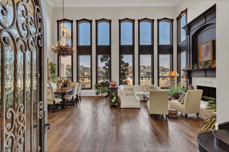 The front door opens into a breathtaking great room, thoughtfully designed for effortless entertaining. Anchored by an impressive hand-carved wood–surround fireplace and framed by soaring two-story windows with tranquil lake cove views, the space is both grand and inviting. Amid the dramatic scale, one might almost overlook the exceptional craftsmanship—custom wood baseboards and intricate trim details that quietly elevate the room. Designer cased doorways seamlessly connect the great room to the kitchen and family room, creating architectural interest and elegant transitions into the heart of the home. The kitchen strikes a rare balance of warmth and sophistication, featuring a thoughtfully designed rock-surround stovetop that serves as a stunning focal point. Expansive granite countertops provide generous and functional workspace, while custom cabinetry showcases refined carved wood rope detailing. Substantial upper and lower storage includes an appliance garage and a walk-in pantry, ensuring both beauty and practicality. Extending the living space outdoors, the expansive second-floor patio flows directly from the kitchen and family room, offering sweeping lake and pool views. A secondary built-in grilling station adds convenience, making this space ideal for gatherings and al fresco dining. The resort-style backyard is a true private retreat. The pool is accented by natural rock formations and cascading waterfalls, with strategically tiered flower beds creating a gentle slope toward the lake’s peaceful cove. Designed for relaxation and enjoyment, the pool includes a sunning ledge, hot tub, and swim-up table positioned at opposite ends. An outdoor kitchen, gazebo, and generous patio seating areas blend modern luxury with natural surroundings, creating a secluded escape. Throughout the home, expansive custom trim, molding, and subtle carpentry details reflect exceptional craftsmanship. This extraordinary home must be seen to be fully appreciated.