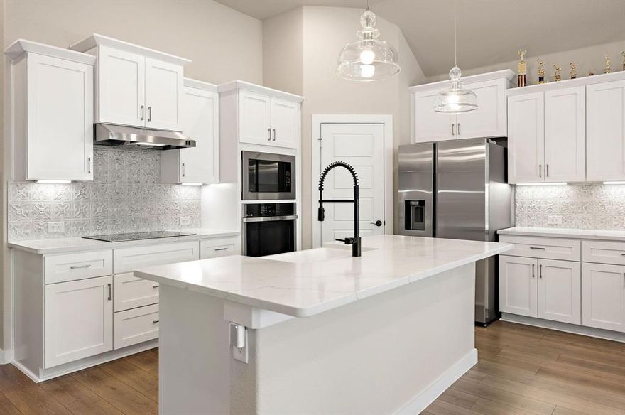 Stunning Modern One-Story K. Hovnanian Home in Justin, TX! This energy-efficient home is designed with an advanced fresh air ventilation system to ensure clean, filtered air for a healthy and comfortable living environment. The open-concept living area exudes warmth and elegance, centered around a striking stone fireplace that adds a cozy ambiance. Expansive windows flood the space with natural light, highlighting the rich textures of the furnishings. The seamless layout integrates the living, dining, and kitchen areas, promoting relaxation and perfect for entertaining.

The gourmet kitchen features elegant Calcutta quartz countertops with striking veining, complemented by custom white shaker-style cabinets with soft-close mechanisms and smart storage solutions. An induction cooktop, farmhouse sink, and stainless steel appliances complete the modern appeal of this culinary space, ideal for both intimate meals and grand gatherings.

The primary suite offers a luxurious retreat with a spa-inspired bathroom, including an oversized shower and a spacious vanity with dual sinks, providing the ultimate relaxation experience. One of the secondary bedrooms includes a private en suite bathroom, perfect for guests. Each bedroom is equipped with generous walk-in closets for ample storage.

Step outside to the expansive covered patio, extending your living space outdoors, perfect for both unwinding and hosting gatherings. This home combines smart technology and luxurious upgrades, offering both elegance and comfort. Located in a vibrant and growing community, this exceptional home is ready to elevate your living experience—don’t miss out!