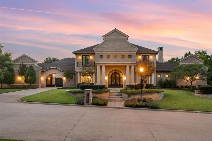 Welcome to a masterpiece of elegance and seclusion in Mansfield’s prestigious Strawberry Fields—a luxury estate where resort living and timeless design unite on two private, beautifully landscaped lots. Behind its stately stucco and stone façade, a grand foyer with a sweeping staircase sets the tone for sophisticated living. Step inside and discover hand-scraped hardwood floors throughout, soaring ceilings, and walls of Custom Marvin windows that bathe every space in natural light. Off the entry, a richly appointed study and formal dining room introduce the home’s gracious flow. The primary wing is a private retreat, complete with a fireside bedroom overlooking the pool, a coffee bar with sink and refrigerator, and a spa-worthy bath featuring a Jacuzzi tub and custom cabinetry. Designed for entertaining, the heart of the home reveals a gourmet Thermador kitchen anchored by a striking custom copper vent hood, two dishwashers, butler’s pantry, and open sightlines to the formal living area and double-sided fireplace. A spacious bar with refrigerator, dishwasher and ice maker connects the formal and casual living areas, creating seamless gathering spaces. A second bedroom suite is conveniently located downstairs. Upstairs, movie nights shine in the media room with popcorn bar, flanked by two additional bedroom suites, a large living area, and a balcony overlooking the grounds. Outside, an award-winning pool—featured on HGTV’s Cool Pools—steals the show, complete with a heated spa, dramatic fire bowls, multiple covered lounges with fireplace and bar, and a secluded lower fire pit. Expansive lawns offer room for play or future additions. A 4-car foam-encapsulated garage, air-conditioned workshop, Control4 whole-home smart system, tornado shelter, pet shower, and abundant storage ensure modern comfort and peace of mind. This is more than a home—it’s a resort-inspired sanctuary, crafted to impress and designed to be lived in beautifully.