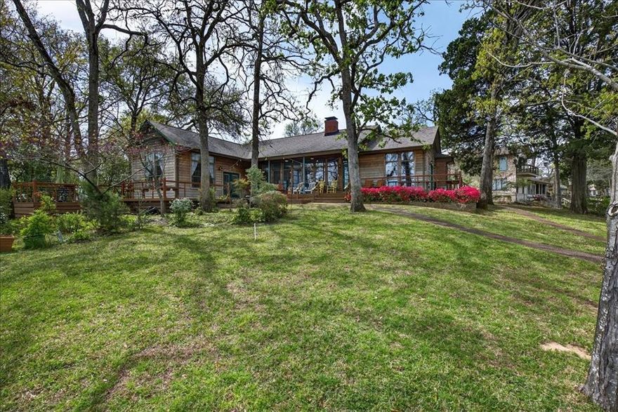 Experience lake living in this stunning waterfront home on Cedar Creek Lake, offering the perfect blend of comfort, relaxation, and breathtaking views. Nestled along the shoreline in a protected cove in the charming community of Enchanted Oaks, this property provides direct water access and unforgettable sunsets that can be enjoyed from the expansive patio and outdoor living spaces. This home offers an open-concept layout, highlighted by a dramatic wall of windows showcasing panoramic lake views. The main living area flows seamlessly into the kitchen and dining spaces. The well-appointed kitchen offers generous cabinetry, ample counter space, and an ideal layout for hosting gatherings. The spacious living and dining areas are anchored by a beautiful double-sided fireplace, perfect for cozy evenings while enjoying the serene lake backdrop. The large primary suite offers stunning water views and features a luxurious bathroom with tub and separate shower. Additional bedrooms provide comfortable accommodations for guests with ample closet space. A separate lockout unit with its own private bath offers flexible space for additional guests, a bunkhouse-style retreat, or potential rental income. Outdoor living is just as impressive, featuring a massive wraparound porch with 180° lake views framed by beautiful landscaping. The two-story boat dock includes electric lifts and an upper-level patio ideal for relaxing by the water.  Additional highlights include a fire pit, fenced yard with gated entry, two-car garage, updated HVAC systems, recent primary bath remodel, and sprinkler pump (2025). For the past decade, the property has also operated as a successful part-time rental through Airbnb, generating approximately $250,000 in income over several years. Whether you're looking for a weekend getaway, investment property, or full-time lakefront home, this is a rare opportunity to own a true waterfront retreat.