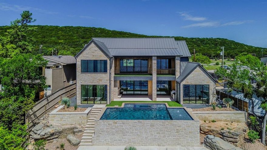 Own the dream lake life everyone dreams of with this quality new-construction masterpiece on the exclusive South side of the Peninsula at Possum Kingdom Lake. Perfectly blending high-end design, breathtaking views, and prime investment potential, this custom modern retreat is now completed just in time for the 2026 Lake Season. Crafted by one of PK’s reputable builders in collaboration with renowned Blake Architects. Positioned to capture sweeping panoramic views over Possum Kingdom’s legendary deep, crystal-clear waters, this striking two-story home features a sophisticated mix of stone, stucco, wood, and brick, accented by bold lines and sleek black windows and doors that frame the lake from nearly every room. With 4,593 sq ft of luxury living (6,221 sq ft under roof), it offers 5 spacious bedrooms, 6 designer bathrooms, and expansive indoor-outdoor spaces built for grand entertaining or quiet lakeside relaxation. Step out to multiple covered patios and porches that lead to a stunning lakeside pool and spa, plus a sunken firepit and a fully equipped outdoor kitchen—setting the stage for unforgettable gatherings as the sun sets over the water. A brand-new double-decker dock is also under construction, complete with a 29-foot boat slip, two PWC slips with lifts and rope swing in some of the clearest, deepest water on PK. Quick boat access to Hell’s Gate, lively waterfront dining, marinas, and all your essentials just minutes away by land. Possum Kingdom Lake is celebrated for its unmatched beauty, exceptional clarity, and vibrant recreational lifestyle, making it one of Texas’s most coveted lakefront markets. Even better, short-term rentals are allowed in only a few areas and this property is in the right place—so you can enjoy personal lake living at its finest while also unlocking excellent income potential. Opportunities like this—brand-new, income potential, fully custom construction, commanding lake views, on the Peninsula, big toy boat dock—are incredible.