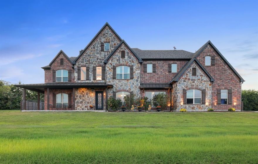 WELCOME TO YOUR OWN SLICE OF PARADISE, WHERE COUNTRY LIVING MEETS REFINED COMFORT! Set on 13.28 picturesque AGG EXEMPT acres with two stocked ponds, mature trees, and sweeping countryside views, this custom-built rock-and-brick home offers peace, privacy, and luxury in one beautiful package. Inside, the main living area wows with a soaring 20-ft ceiling, wood crossbeams, and a floor-to-ceiling stone fireplace—perfect for cozy evenings. The chef’s kitchen features an 8-ft island, custom cabinetry with under-cabinet lighting, black stainless appliances, granite counters, a walk-in pantry, and a breakfast nook with its own TV for relaxed mornings. Also, downstairs are a spacious guest or in-law suite, a generous game room, and a dedicated office with elegant 8-ft double doors. Hand-scraped hardwood floors, tall ceilings, graceful chandeliers, and detailed crown molding bring warmth and sophistication throughout the home. Upstairs, the private primary suite offers a tray ceiling, spa-inspired travertine bath with dual shower heads, a jetted tub, and an enviable walk-in closet with seasonal storage. Two additional bedrooms each include ensuite baths and walk-in closets. The utility room is thoughtfully designed with a sink, drying rack, and dual attic access, including one walk-out attic with abundant storage. Outdoors, enjoy endless possibilities: a large, covered patio for entertaining, a 30’x40’ shop with electricity and RV hookup, sprinkler system, and two loafing sheds for animals. A charming, gated entrance with stone columns, Texas-star gate, and black pipe fencing welcomes you, while the expansive backyard—enclosed by an 8-ft privacy fence—offers plenty of room to add your dream pool. 
Additional highlights include a 3-car garage with handsome wooden doors, an above-ground safe room, and three HVAC units. Whether you’re seeking farm life, a private retreat, or a luxurious homestead, this property perfectly captures the serenity and style of country living.