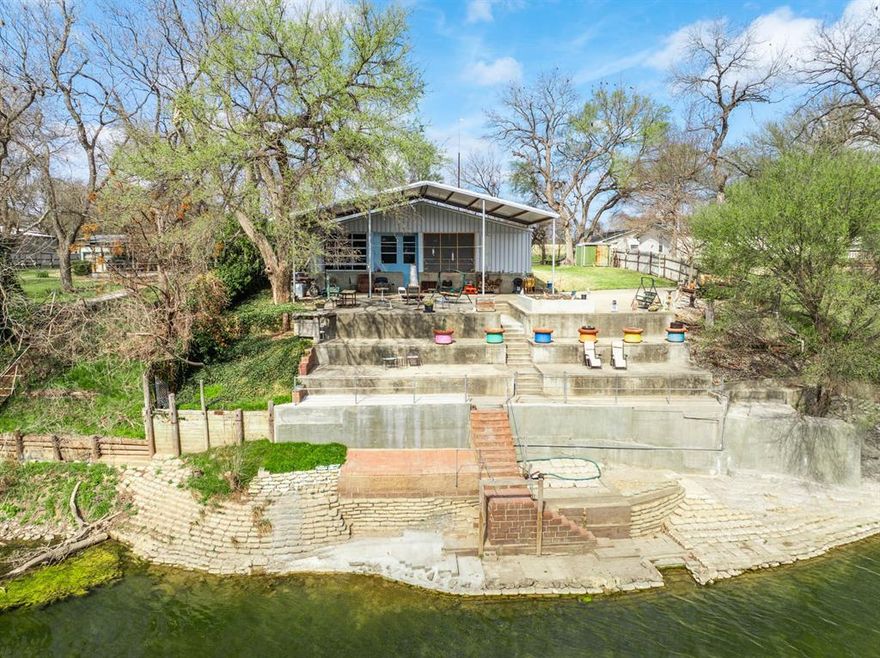 Stunning riverfront retreat on the Brazos River! This 1-bedroom, 1.5-bathroom metal frame home built in 2019 sits on 0.38 acres in Clifton, Texas located in the Clifton School District. The main home offers 1,082 square feet, plus an impressive 1,922 square foot den addition that has been converted into a game room-den with garage area. The home features vinyl flooring throughout for easy maintenance. The kitchen showcases granite countertops, a 4-burner gas stove, dishwasher, and a large pantry for ample storage. A breakfast area provides casual dining space. The master bathroom features dual sinks and a large shower. A separate laundry room adds convenience. The home has a metal roof and is on a septic system. Outside, enjoy a covered back porch with large bay doors that open up to the game room-den area, perfect for indoor-outdoor entertaining. A large cement pad provides excellent space for outdoor entertainment and gatherings. The property features concrete steps leading all the way down to the Brazos River, with the structure recently reinforced for safety and durability. Residents have access to a private boat ramp exclusively for property owners. Whether you're looking for a vacation home or full-time river living, this property offers unbeatable Brazos River access and modern amenities in a serene setting!