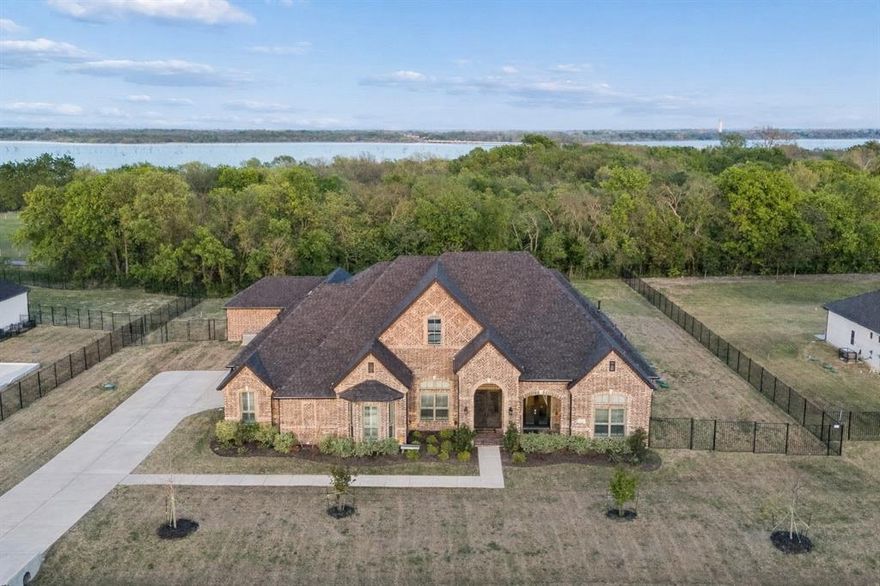 An entertainer’s paradise awaits in the peaceful community of Lakeview Downs—just minutes from the water, yet worlds away from the noise and lights of the city. Backing to Corps of Engineers land and Lake Lavon, this exceptional home offers privacy, luxury, and unforgettable outdoor living. Step inside to an impressive open-concept floor plan, where a soaring vaulted ceiling crowns the expansive great room. The space flows seamlessly into a chef’s dream kitchen featuring a large breakfast bar island, induction cooktop with pot filler, double ovens, custom glass display cabinetry with integrated lighting, and even a built-in dog-feeding station with its own water source. From the main living areas and the primary suite, take in views of the show-stopping backyard—highlighted by a custom designed pool. This fully automated oasis features an infinity-edge spa, in-water table and seating area, oversized tanning ledge, deck jet laminar water features, a dramatic 6-foot sheer descent waterfall, and remote-controlled gas fire bowls—creating a resort-style experience right at home. The oversized primary suite offers a true retreat, complete with automated window treatments including blackout shades, a spa-inspired en-suite bath with dual vanities, soaking tub, luxurious separate shower, and an expansive walk-in closet. Entertainment continues indoors with a large game room featuring a wet bar and full bath, along with a dedicated media room perfect for movie nights or game days. Each secondary bedroom is generously sized and includes its own private full bath. Additional highlights include tankless water heaters, a backup generator, a wood-burning firepit, and a spacious 3-car garage. This is more than a home—it’s a lifestyle.