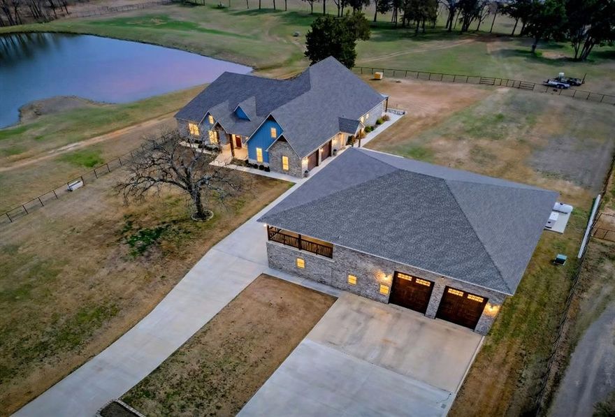 31.8-acre estate in the heart of North Texas horse country! Approx 800 Ft. of road frontage & a private electric gate. The main home spans 5,472 total square feet (3,376 Sq Ft of living space) & is thoughtfully designed with 4 beds & 3 baths, filled with abundant natural light throughout. The kitchen features a large walk-in pantry, gorgeous custom cabinets, & seamless flow into a dining room bathed in natural light. A propane fireplace anchors the living area, creating warmth & charm. The primary suite is highlighted by a spa-inspired bath with a Jacuzzi tub beneath a stunning chandelier. Heated floors in the primary bath, closet, & laundry room provide everyday comfort. A large game room with full bath overlooks the in-ground pool & hot tub, creating the perfect entertaining space. Step outside to enjoy a 932 Sq Ft L-shaped covered patio, outdoor shower, pool room for storage & an in-ground safe room. 907 Sq Ft two-car garage-heated & cooled - with an electric vehicle plug. The property is equipped with a 400-amp generator, 500-gallon propane tank, 260-Ft water well, 2-way water system & irrigation system. For those seeking multi-generational living, income potential, or a recreational retreat, the 7,021 Sq Ft shop is a rare find. It includes 968 Sq Ft of main-level living space with a full bath, 967 Sq Ft upper-level with full bath & kitchenette, plus a 1,468 Sq Ft covered balcony. There’s dedicated space for 2 campers with full hookups & sewer drain, along with a 3-car carport. Equestrian & agricultural enthusiasts will love the 50x50 metal barn, corral, pipe fencing with no-climb wire, & Bermuda grass pastures with Ag exemption. 2 stocked ponds complete the picturesque landscape, making this property ideal for horses, cattle, or simply enjoying Texas skies. Whether you envision a multi-generational estate, a private ranch retreat, an equine facility, or a hobby farm with luxury amenities, this remarkable property offers unmatched versatility and opportunity!