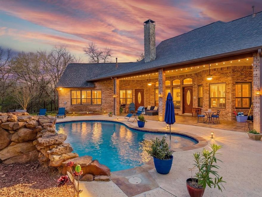 PRICED $70K BELOW CERTIFIED APPRAISED VALUE, NO CITY TAX,MUD! + 2% concession with preferred lender! Escape to your own private resort on nearly 2 acres in the Oak Shores lakeside community, where towering trees, resort-style pool, and timeless architecture create a setting that feels worlds away from the city, yet minutes from everyday conveniences.This thoughtfully designed home features 5 bedrooms, 3 bathrooms, and a 3-car garage. Interior highlights include solid wood doors imported from Boston, hardwood floors, plantation shutters, cedar beams in the living room, custom lighting, and a stunning gazebo-style ceiling in the breakfast area.The gourmet kitchen is designed for both everyday living and entertaining, Viking appliances, quartz countertops, a large island, dual oversized sinks, custom cabinetry, built-in wine refrigerator, and a butler’s pantry. The primary suite offers a cozy fireplace, serene views of the pool and surrounding trees, and a luxurious bath featuring a steam Jacuzzi. Flooring throughout the home includes travertine marble, slate tile, and hardwoods, adding warmth and character. Step outside to your private backyard oasis, complete with a 25,000-gallon heated saltwater pool with a dramatic Oklahoma rock waterfall, creating a resort-style retreat. Additional electrical connections near the pool and a concrete slab with water and electric hookups allow for future outdoor structures. Additional features include an imported Italian fountain at the front entrance, triple insulation, private water well, wrought iron fencing, whole-home intercom and stereo system, new HVAC installed 2 years ago, two hot water heaters, and recently repainted interior and exterior. Close proximity to the tollway and I35. Minutes away from the highly anticipated new high school to be completed in 2026-2027. A rare opportunity to own a truly special property where privacy, nature, and timeless design come together.