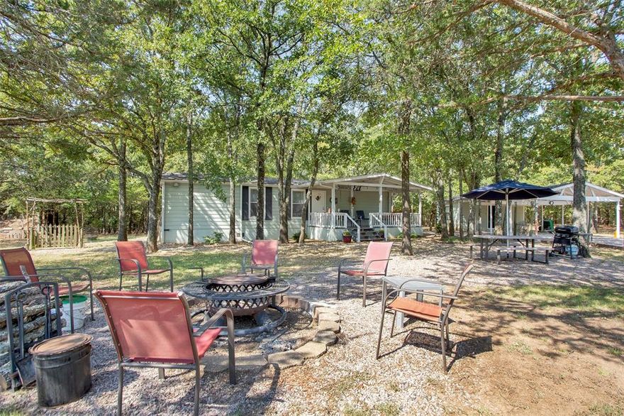 Peaceful 10.5-Acre Retreat Just Minutes from Lake Texoma in Sadler, Texas in booming Grayson County! This property offers the perfect mix of privacy and nature. Tucked away in the woods and set back from the road, the adorable and meticulously maintained MOVE-IN ready singlewide mobile home with 2 bedrooms and 1 bath serves as a tiny home, weekend retreat, guest house, or even as a temporary home while you build your dream barndominium or custom residence. Sip coffee on the front porch as you take in the country views and relax on the screened-in back porch overlooking the woods. Multiple picture-perfect build sites on the property offer flexibility for your future plans. All utilities are already in place, including multiple water sources along the rock driveway. A double carport with small workshop provides storage. The impressive 30x40 metal pole-barn shop (built in 2017) — features two roll-up doors, concrete floor with drain, utility sink with water heater, industrial ceiling fan, welder hookup and multiple electric outlets including 220V and 110V quad. Located just 6 miles from Big Mineral Resort & Marina at Lake Texoma, this rectangular, fully-fenced parcel features approximately 308 feet of road frontage and roughly 1,550 feet of depth offering space for play and privacy. At the front of the property is a pasture ideal for livestock or horses. The back of the property is heavily wooded, with a private, park-like setting that adjoins scenic Hickory Creek. Well-maintained trails wind through the trees — perfect for exploring, four-wheeling, or simply enjoying the abundance of wildlife, including deer. Conveniently located just minutes from Hwy 377, with quick access to US-82 and to Whitesboro, Sherman, and Gainesville. Zoned to desirable Whitesboro ISD. Whether you’re dreaming of a recreational getaway, a spot for your dream home in the country, or a combination of both — this property delivers it all!