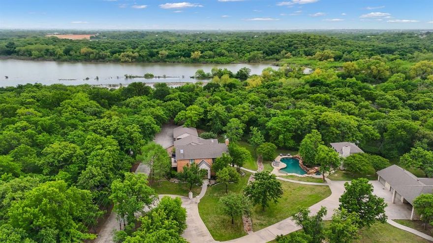 A rare opportunity to own this private, fully fenced 2-acre property with direct access to Lewisville Lake. Currently used as a very successful Short Term Rental, booked approx 80% of the time. This one of a kind estate has a main house with 3 bedrooms, 3.5 bathrooms, with many large picture windows, a resort style pool with spa and cascading waterfalls, outdoor grill and an 890 sqft pool house with full kitchen, fireplace and a second story with large bedroom that sleeps 9 and a full bathroom. Enter this large property through the electric gate to a circular driveway, spanning over 300 feet of concrete to rolling lawns, a creek and many mature trees. The property has 4 garages with built-in storage for 4 cars (2 car + 1 car + 1 car + a golf cart garage) an RV carport for RV or boat parking. There is also a 871 sqft separate workshop, currently being used as a game room, with tons of built-in storage, shop lighting, a sink and refrigerator. Located only 10 minutes from the city of Denton, yet feels like you are isolated in the forest. There is a separate fence to access the trail down to the lake with private beach. Don’t miss this exclusive opportunity for this one of a kind lake front property.
The home is currently being used as a short-term rental. Contact listing agent Christine for available showing times between bookings.