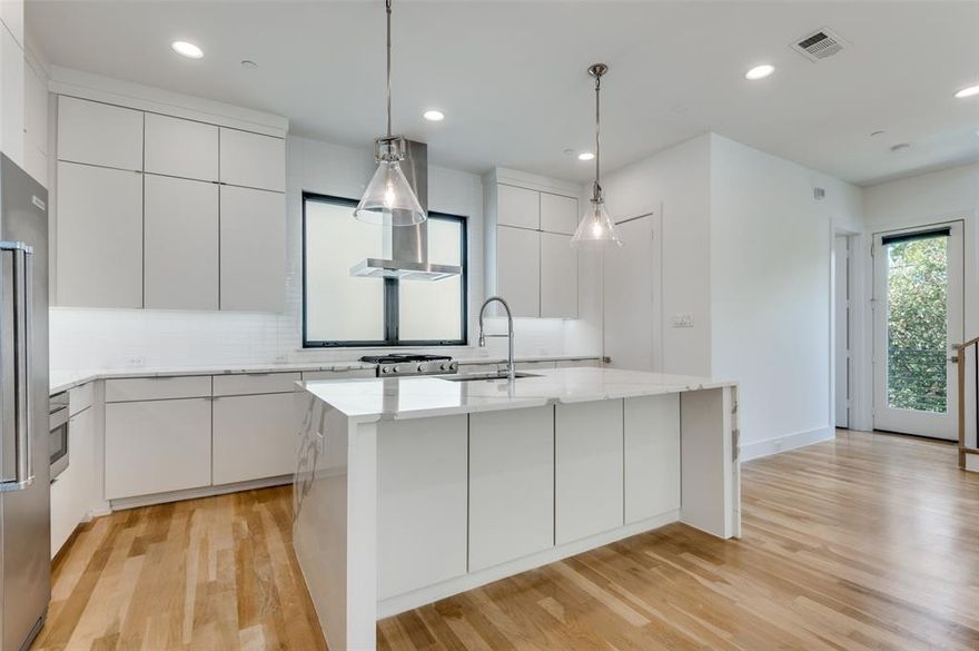 Rare Front Unit! Gorgeous contemporary townhouse, adorned with additional windows throughout, offering an abundance of natural light, spaciousness + a touch of modern aesthetic.  Only unit with a balcony off of the living room. Premium embellishments include light maple wood flooring, oversized quartz waterfall island, built-in SS refrigerator & window treatments in every room. Gourmet kitchen has gas range with griddle, vent a hood + large waterfall island with additional seating, optimal for entertaining. Impressive large windows cultivate open concept + large living room foster's relaxed living and generous space for any design layout. Primary bedroom has wood flooring and bathroom has oversized shower, decorative marble tile and large walk-in closet. Patio yard has privacy fence, perfect for outdoor retreat, grilling or pets. Nest thermostat & google doorbell. BONUS Electric car charger in garage! Close to Love Field & UTSW.