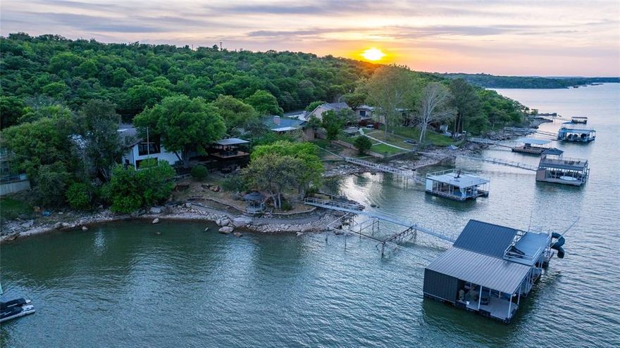 Welcome to 440 Lakeside Drive, a premier lakefront property on Lake Brownwood offering over 6,500 square feet designed for waterfront living and large-scale entertaining. This split-level home features six bedrooms and six full bathrooms with two complete living environments, including two kitchens, two living rooms, two dining areas, and two walk-in pantries, providing flexibility for guests or multi-use living. The main level showcases vaulted wood ceilings, a rock fireplace, open-concept living, and a spacious kitchen with island, while the lower level offers a full second residence with its own kitchen, living room, rock fireplace, dining area, and private access. Outdoor amenities include multiple decks, covered patios, a stone entertaining area, covered parking, and a convenient exterior door leading directly into a bathroom from the porch. The private dock sits in deep water on the main body of the lake and features three slips, two HydroHoist boat lifts, four jet ski docks, a sun deck, fish cleaning station, and storage. Designed for both everyday comfort and hosting, this property combines space, functionality, and direct lake access in one complete offering.
