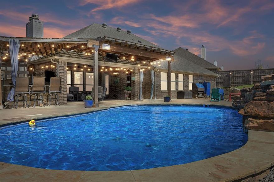 Beautiful newer 3-bedroom, 3-bath home with approximately 2,384 square feet, a heated pool, and exceptional indoor-outdoor living in Fort Worth near Eagle Mountain Lake. Filled with natural light, this home offers no carpet, neutral colors, recessed lighting, gorgeous hardwood flooring, and airy tile throughout. A private office with French doors sits just off the entry, while the open-concept kitchen and living area is designed for both daily living and entertaining. Kitchen features include custom quartz countertops, undermount sinks, stainless steel gas cooktop, double stainless steel gas convection ovens, built-in microwave cabinetry, stainless steel dishwasher, and a newer high-end refrigerator that remains with the home. The living room features a tucked-away corner fireplace that adds warmth and charm. The primary bath includes double vanities, a stand-alone garden tub, and separate tiled shower. Outside, enjoy a front porch sitting area, terraced backyard with stone retaining wall, heated chlorine pool with rock waterfall feature, and an extended covered patio with pergola styling. The outdoor living space is complete with a granite bar top, built-in grill, refrigerator, fully bricked woodburning fireplace, infrared heater, and ceiling fan. Conveniently located near parks, shopping, dining, Fort Worth Meacham International Airport, the Fort Worth Stockyards, and Eagle Mountain-Saginaw ISD.