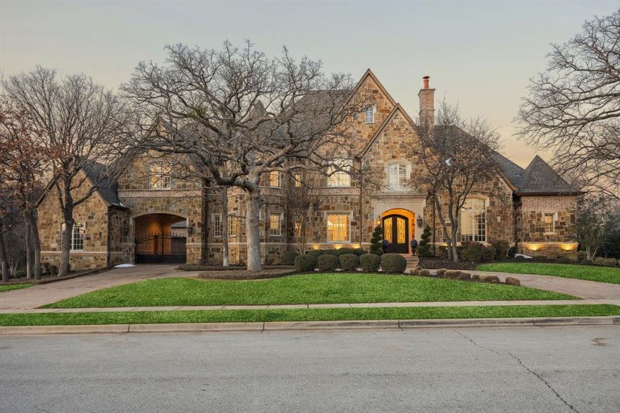 Exceptional by design, extraordinary by nature. Commanding a private, wooded sanctuary in the heart of Southlake's most coveted neighborhood, this 7,442 sq ft home presents a rare opportunity to experience refined living. Classic architectural distinction meets contemporary luxury across 5 ensuite bedrooms & thoughtfully curated spaces designed for the most discerning homeowner. The gated porte cochère motor court establishes immediate distinction, offering privacy & a refined sense of arrival. Step inside to discover a thoughtfully designed floor plan featuring formal living & dining rooms adorned w designer lighting, rich hardwood floors, & elegant marble accents. The gourmet kitchen showcases a premium Sub-Zero & Thermador appliances, an oversized island w leathered granite, & a walk-in pantry. The adjacent breakfast room provides an inviting setting for casual family meals, while the private study—complete w custom built-ins & a cast stone fireplace—offers a serene sanctuary for work. The first-floor primary suite is a true retreat, featuring a cast stone gas fireplace, sophisticated dry bar, & spa-inspired ensuite w two vanities, walk-in glass shower, & soaking tub. The expansive closet w custom built-ins & dedicated gym space or nursery w patio access completes this luxurious sanctuary. A second first-floor ensuite bedroom accommodates multigenerational living or distinguished guests. Entertainment reaches new heights w the tiered media room, featuring professional lighting & custom projection screen, while the upstairs game room w wet bar & three additional ensuite bedrooms provide private retreats for family or guests. The outdoor spaces transform the grounds into a resort-style sanctuary. The covered patio showcases a complete outdoor kitchen, custom stone fp, & sparkling pool & spa surrounded by mature landscaping. This exceptional estate represents more than a home—it is a lifestyle statement where every detail delivers comfort, luxury, & functionality.