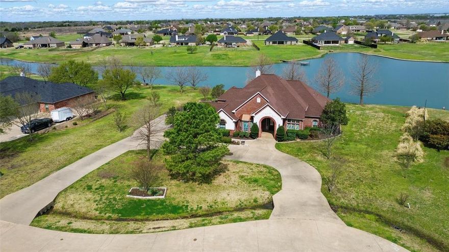 Welcome to this rare and stunning waterfront property nestled on 1.825 acres in the highly sought-after Shamrock Ridge community in Forney. This expansive 3,524 sq. ft. home offers an impressive blend of elegance, functionality, and serene lakefront living. Inside, you'll find 4 bedrooms, 3 full baths, 2 spacious living areas, 2 dining areas, a dedicated office, and an in-law floorplan — thoughtfully designed for comfort and versatility. Crown molding flows throughout the home, adding a timeless touch of sophistication. The heart of the home features a warm and inviting stone gas log fireplace in the main living room, seamlessly opening to the kitchen and breakfast nook. The kitchen is beautifully appointed with granite countertops, rich oak cabinetry with a decorative vent hood, a convenient island, gas cooktop, and walk-in pantry — perfect for gatherings and entertaining. Just off the kitchen, a formal dining room awaits, highlighted by elegant wood trim and a trey ceiling. A private home office with French doors and a bay window offers a quiet space to work or study. The owner’s suite is a true retreat, complete with a cozy sitting area and built-in bookshelf, an oversized custom walk-in closet, and an ensuite bath featuring a garden tub, dual vanities, separate shower, and upgraded smart mirrors. Two additional bedrooms share a convenient Jack & Jill bath, while the fourth split bedroom is tucked away with its own full bath — perfect for guests, in-laws, or a private suite setup. At the back of the home, the light-filled sunroom or second living area boasts breathtaking water views, creating the perfect spot to relax and unwind. Outside a beautifully landscaped yard leads to your private fishing dock — an angler’s dream! Located on a quiet cul-de-sac in Forney ISD, this property also features a 3-car garage and offers a rare opportunity to own waterfront living with the space and privacy you’ve been searching for.