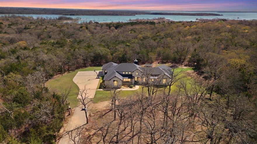 Rare opportunity to own a meticulously designed custom home on 7 private, tree-covered acres just minutes from Lake Ray Roberts, I-35,& Hwy 377. 
A winding driveway leads through the trees to the secluded homesite, creating a peaceful retreat surrounded by nature.
Designed with both comfort and entertaining in mind, the home features an open-concept layout with soaring ceilings, exposed wood beams, and large windows that capture beautiful views of the surrounding acreage. The living area is anchored by a striking double-sided fireplace with an electric fireplace inside & a wood-burning fireplace extending to the outdoor living space.
The chef’s kitchen includes a gas cooktop, stainless appliances, commercial-grade built-in refrigerator, built-in oven and microwave, ice maker, pull-out beverage cabinet, walk-through pantry, & custom soft-close cabinetry with pull-out drawers.
The home offers three spacious bedrooms, each with its own custom closets with generous storage & shelving, ensuite bathroom featuring walk-in showers, while the primary suite includes a soaking tub. A flexible office provides additional space for work or hobbies, & a convenient half bath serves guests.
Outdoor living is equally impressive with a covered patio, outdoor kitchen featuring a Green Egg smoker, Blackstone griddle & beverage fridge. The property also includes a two-car garage with storage, mudroom entry, and a laundry room designed for organization with pull-out storage & fold-out drying racks.
 
Property Highlights
• Custom built one-owner home
• 7 private wooded acres with underground electric fencing
• 3 bedrooms with ensuite bathrooms
• Flex room or office space
• Covered outdoor kitchen & entertaining patio
• High-end cabinetry & storage throughout including a hidden safe room
• Secluded setting just minutes from Lake Ray Roberts & I-35

Opportunities like this are rare—schedule your private showing today.