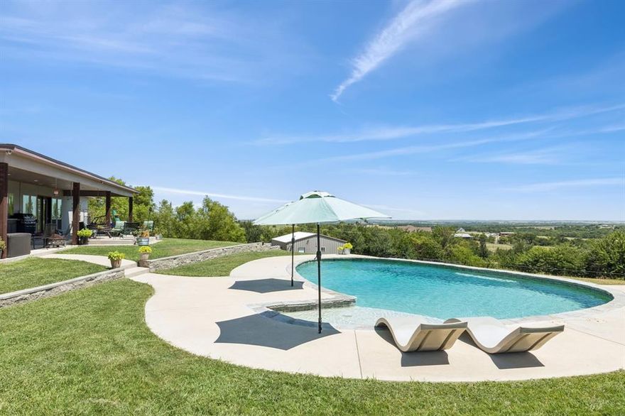 5 SPRAWLING ACRES! RESORT STYLE POOL! EXCEPTIONAL VIEWS! CUSTOM DESIGNED AND BUILT HOME! 2 LAUNDRY ROOMS! Experience luxurious country living in this stunning 4-bedroom, 4 full bath, 2 half bath custom home set on 5 scenic acres with breathtaking elevated views. Boasting great curb appeal, thoughtful landscaping, and a sparkling pool, this home offers the perfect blend of elegance, comfort, and function.

Step through double wrought iron doors into a unique, well-designed floorplan featuring stained concrete floors, vaulted ceilings, recessed lighting, and multiple living areas. The heart of the home is the peninsula-style kitchen, complete with decorative lighting over the breakfast bar, stainless steel appliances—including a 6-burner gas range with griddle, pot filler, beverage fridge, and a large single basin sink—all nestled between two spacious living areas. One features a dramatic floor-to-ceiling fireplace and built-in speaker system; the other provides direct access to the patio. 

The split-bedroom layout offers a luxurious primary suite with a decorative chandelier, spa-inspired ensuite with a massive walk-in shower featuring 4 showerheads and 5 body sprays, a jetted tub, dual vanities, and an enormous walk-in closet with stackable washer & dryer hookup. Each of the three secondary bedrooms has its own private bathroom and walk-in closet.

A fully equipped media room and unique rotundas with stairs leading to loft spaces (perfect for playrooms or storage) add extra function and charm.

Enjoy outdoor living on the oversized covered patio with built-in storm shelter, overlooking a resort-style pool with tanning ledge. A spacious workshop with electricity offers space for hobbies or storage, and includes a full bath and bonus space great as a bedroom or office.

This property is a rare find— subdivided from a larger tract, it includes the home and 5 private acres of rolling views and peaceful living.