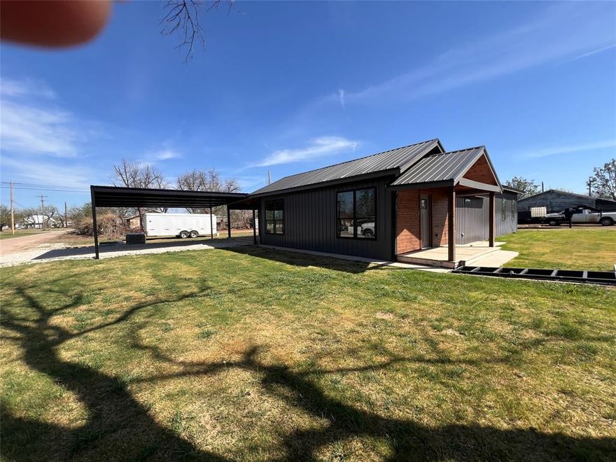 Featuring 3 bedrooms and 2 bathrooms, this home welcomes you with a spacious living room showcasing a vaulted ceiling, accent wall with a cozy electric fireplace, and LVP flooring. The kitchen is designed for both function and style, offering a huge island, an abundance of cabinets, expansive granite countertops, and a large walk-in combination pantry-utility room. The primary bedroom shines with an ensuite bathroom with dual sinks, a standalone tub, and separate shower.  A portion of this home was originally built in 1934. That portion was completely gutted and a large addition added starting late 2024. Everything is NEW, including plumbing, electrical, fixtures, and all finishes throughout.  Sitting on a corner lot just under half an acre, the property also includes a cellar, working water well, a huge covered back porch, Class 4 metal roof, partial metal fencing, and a 2-car carport. Completion is expected within 30 days, giving you the opportunity to be among the first to enjoy this fully updated and move-in ready home. Builder's finish out plans subject to change but right now LVP is planned for main areas with carpet in the bedrooms.  NOTE: Door will be installed on the cellar OR if buyer doesn't want the cellar, the owner will have it filled in.