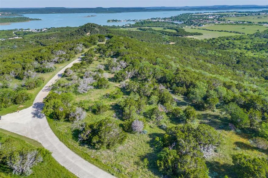 1.656 Acres of Unforgettable Views and Unmatched Luxury at The Ranch on Possum Kingdom Lake! Perched high on a scenic plateau, 1099 Highland Drive offers a rare opportunity to design and build the custom home of your dreams with breathtaking panoramic views of Possum Kingdom Lake and the lush valley below on a naturally level homesite, thoughtfully tucked among trees for ultimate privacy. Imagine evenings spent watching spectacular sunsets melt into a star filled sky this is your own piece of Texas heaven. This elevated homesite is one of the most sought-after locations in the prestigious gated community of The Ranch, where rustic charm meets refined luxury. As a property owner, you'll enjoy resort-style amenities including a million-dollar infinity pool and hot tubs with a waterfall edge overlooking the lake, a lakeside firepit and grilling stations perfect for entertaining, and a courtesy boat dock for easy access to The Cliffs and iconic Hell’s Gate. Outdoor enthusiasts will love the private equestrian center with stables, a riding arena, and miles of scenic trails, as well as tennis and sandpit volleyball courts, a skeet shooting range, and over 1,100 acres of common area to explore on horseback, ATV, or foot. You'll share this pristine land with deer, native wildlife, and vibrant wildflowers a true Texas luxury lifestyle that blends rugged natural beauty with elite comfort. Whether you're building a weekend retreat or your forever home, 1099 Highland Drive is more than just a homesite, it's an invitation to live the dream.