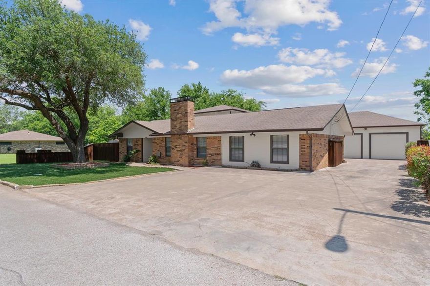 Meticulously maintained and thoughtfully designed, this property is an exceptional fit for buyers who value space, organization, and a true shop setup. The home sits on a beautifully landscaped lot featuring low-maintenance turf grass, a fenced yard, a welcoming back porch, and an additional storage building—ideal for both relaxation and utility. Inside, the layout offers generous living areas including a cozy family room with a wood-burning fireplace, two dining spaces, and a well-appointed kitchen with custom ash cabinetry, an island, and a utility room with dual pantries for excellent storage. The primary suite is designed for comfort and function, featuring separate vanities, walk-in closets, a garden tub, and an oversized shower. Upstairs, a massive bonus room provides flexible space perfect for a home office, studio, or additional living area. Additional two secondary bedrooms downstairs. The standout feature is the impressive detached garage—fully equipped with extensive tool storage and a convenient half bath—making it an ideal setup for a mechanic, car enthusiast, or serious hobbyist. Clean, spacious, and move-in ready, this property offers a rare combination of comfort, functionality, and specialized workspace in a convenient location.