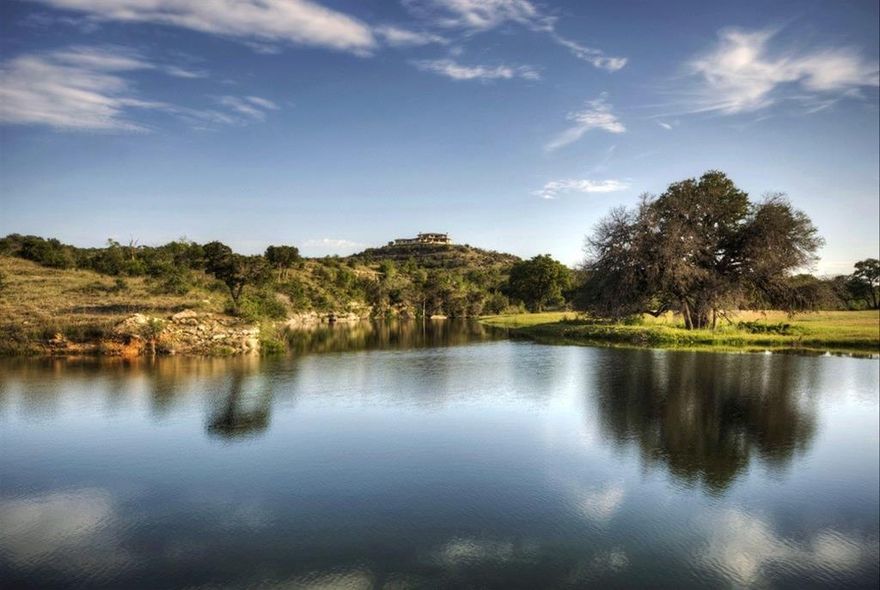 Unparalleled 855-acre live water ranch in the heart of Texas Hill Country, just west of Dripping Springs and 45 minutes from downtown Austin. This ranch offers extraordinary improvements and incredible views with nearly 1.5 miles of spring-fed Mustang Creek flowing year-round, even through drought. The creek is dammed up to create several deep lakes perfect for fishing, swimming, paddleboarding, etc. Also within 30 minutes is the vineyard region between Johnson City and Fredericksburg as well as Wimberley.

The ranch's topography is diverse with dramatic valleys and soaring hilltops that provide breathtaking panoramic views. Perched atop one of these hilltops is a 7,000 sqft custom home featuring 6 bedrooms, 7 bathrooms, and upgrades throughout including new hardwood floors, a state-of-the-art kitchen with new appliances, and a new Savant AV control system. Step outside to enjoy the negative-edge pool and outdoor living areas with sweeping vistas.

This ranch is incredibly private and is accessed by a gated, private 1-mile paved road and is completely high fenced. Upon entering the gated entry, there is a large pond, incredible wildlife is abundant throughout the ranch. Included on the ranch are 10 deer feeders, 6 turkey feeders, and 6 food plots, ensuring a healthy habitat for a wide variety of wildlife. The ranch is under wildlife management.

Additional structures closer to the creek include a rustic guest house, a foreman’s house, a nice moderately-sized equestrian facility and a large equipment barn.

Whether for hunting, fishing or recreational enjoyment, this ranch is a truly exceptional property offering the best of Texas ranch life.