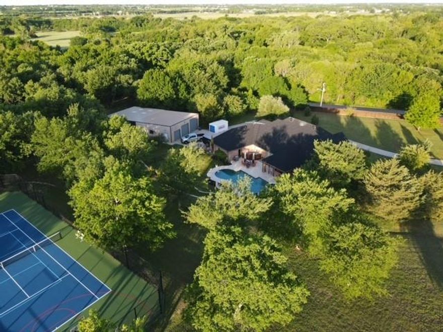 Combines two parcels of land (over 6 acres of this property is Ag exempt). Private paradise in Sanger, Texas, just 10 minutes from Razor Ranch. Beautiful 4-3-3 home on two lots ~ 10.82  acres. Heavily wooded acreage with private tennis - pickleball - basketball court, pool with spa built in 2018, shop with RV parking, and guest or office quarters with full bath. 
This beautiful pool and spa are supplied with crystal-clear well water (no water bill here). Pool and spa heated by an owned propane tank. An Endless Pool system. Low chlorine, ozone filter system.
Professional tennis court with pickleball and adjustable basketball hoop.
Private shooting range. Hilltop fire pit.
Insulated metal building 1600 sf with an additional 1600 sf undercover, complete with office or guest quarters with full bath. RV parking.