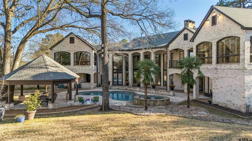 Nestled on a rare, sprawling one acre, corner lot overlooking holes 7 & 9 of the prestigious Hollytree Golf Course, this truly one of a kind estate offers unmatched privacy, space, & resort style living. With over 8,100 square feet of thoughtfully designed living space, this home is equally perfect for those seeking a move in ready luxury retreat or a canvas to make your own. From the moment you arrive, the grand curb appeal & iron double doors set the tone. Step inside to soaring ceilings &dramatic floor-to-ceiling windows that frame breathtaking views of the expansive backyard, sparkling pool, & several outdoor living spaces, creating a seamless indoor and outdoor flow ideal for entertaining & everyday living. The gourmet kitchen features an oversized bar, Wolf double ovens, two microwaves, generous prep space, & a scullery featuring an additional dishwasher, ice machine, & mini fridge. Just off the breakfast area, a side patio with outdoor kitchen offers the perfect spot for casual meals or gatherings. An entertainer’s game room spans 1,288 square feet upstairs with a theater projection screen, theater seating, full wet bar, full bath, & sweeping golf course views, ideal for movie nights, game days, or hosting unforgettable gatherings. The main level offers three guest suites, all with en suite baths, a den with another full bath, laundry room, & tranquil courtyard. The luxurious primary suite is a true sanctuary with a wall of windows with plantation shutters overlooking  the golf course & a resort like bath with floor to ceiling marble, separate vanities, his & hers closets, oversized shower, & separate soaking tub. Outside is a true oasis with a large yard, pool, gazebo, yard space, 3.5 car garage & large driveway with plenty additional parking space. This extraordinary Hollytree estate is a rare opportunity to own one of the most impressive homes in the community where privacy, luxury, & lifestyle meet.