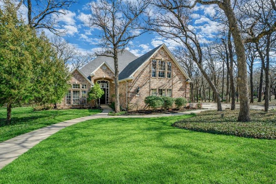 Nestled on a beautifully wooded .67-acre corner lot in the private, gated community of Corinth Forest, this custom two-story home offers exceptional privacy and refined comfort. Featuring 4 bedrooms, 2.5 baths, and a striking 14-foot wood-beamed office that can serve as a fourth bedroom, the home showcases thoughtful design throughout, including a split-bedroom layout, walk-in closets, solid core 10-foot doors, ceiling fans, breakfast bar, and abundant built-ins. The first floor is enhanced by custom decorative stamped and stained concrete flooring, detailed crown molding, and 6-inch baseboards. A dramatic 22-foot vaulted living room with two-story plantation shutters frames breathtaking views of the covered two-tier deck and adjoining Army Corps of Engineers wooded property. The backyard is a true retreat with a trellis, pond and fountain, winding flagstone path, and attached stone fire pit, all backing to Veal Branch Springs Creek just steps away as it flows toward Lewisville Lake. Residents enjoy neighborhood amenities including a private stocked fishing pond with lighted fountain, pool, tennis and basketball courts, and park areas. Modern conveniences include hardwired Cat-7 fiber internet with 2GB capability, wireless access points, multi-camera monitored security, voice-controlled multi-room media, WiFi lighting, Alexa integration, Google Nest thermostats, and three HVAC systems (including new upstairs unit in 2024). Additional updates include fresh paint (2026), new plush carpet in the primary suite (2026), and complete aerobic septic system component replacements (2022–2024). A 250-gallon propane tank services the custom cast stone gas fireplace, water heaters, and gas dryer. The oversized 3-car garage features insulated steel-back doors for climate moderation and ample space for a boat or workshop and Tesla charging station. An irrigation system completes this exceptional property surrounded by abundant wildlife and serene natural beauty.