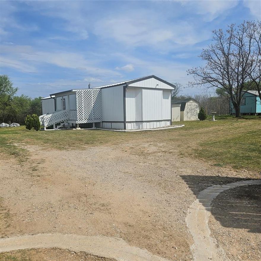 Impressive two bedroom one bath home with large living area open to eat in kitchen with gas range on just over 1 fenced acre that has a seasonal creek at rear of property.   Full washer and dryer hook ups are located in hallway right between the two bedrooms .One thing unique about property are the small boxed in trees inside fence and just outside of fence lines that have a timed sprinkler system to each boxed in tree.  There are two storage buildings, one with electricity that would make a small shop for dad and his tools.  It's unrestricted and minutes to major highways to the bigger cities  of Mineral Wells and Weatherford and that means shopping too.