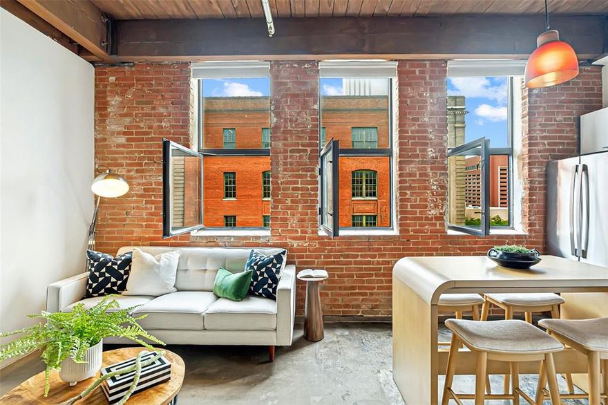 This Elm Place Residence offers an authentic loft aesthetic with exposed brick, cedar beams, concrete floors, and three working casement windows that fill the space with natural light. Historic character is complemented by meaningful updates, including a new HVAC system, refrigerator, washer, and dryer. The open layout lives comfortably with flexible living and dining spaces, plus a dedicated bedroom area with ceiling fan and a large walk-in closet. The modern, sleek kitchen features wood cabinetry, marble waterfall countertops, stainless steel appliances, and ample storage and prep space. The beautifully updated bathroom offers herringbone tile, an updated vanity, a large tub and shower combination, and built-in linen shelving. A side-by-side in-unit laundry area with additional storage adds everyday functionality. Building amenities include 24-hour security, secured garage access, a fitness center, and a landscaped courtyard. Outside, you are moments from Dealey Plaza, American Airlines Center, Downtown, the West End, Victory Park, Trinity Groves, restaurants, entertainment, and major downtown access. A DART station just a block away provides convenient access across Dallas and beyond. Reserved parking spaces beneath the building are available for lease at approximately $150 per month. A true lock-and-leave loft offering historic character, stylish updates, and a location that puts Downtown Dallas at your door.