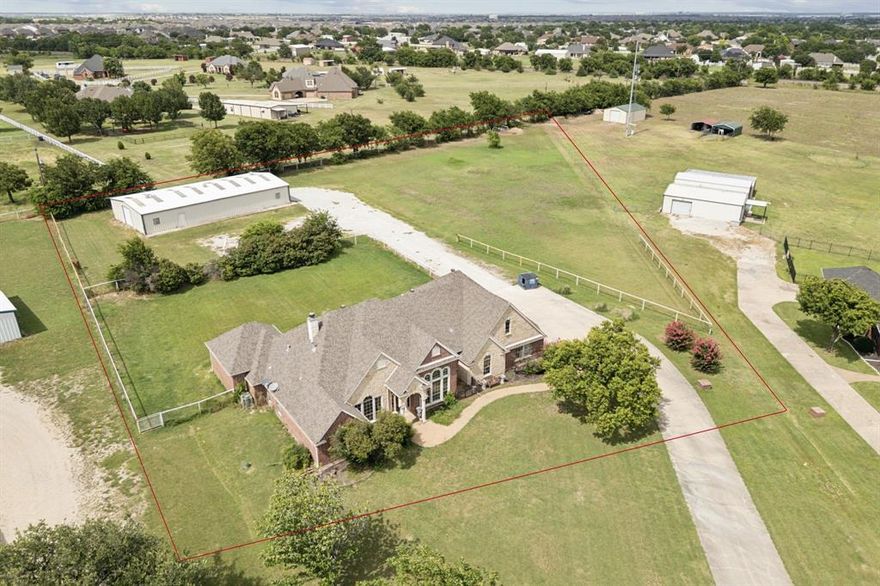 Did you know that you can get an 80 X 40 WORKSHOP, PLUS a true custom masterpiece home on 2.5 acres in the unincorporated area of Haslet— offering rare freedom from city taxes and water bills? This executive brick-and-stone residence spans 3,450 SF and is complemented by an impressive 80' x 40' workshop, complete with electricity, water, sewer, four oversized roll-up doors, storage galore, drive thru capabilities & dual RV hookups—a dream setup for entrepreneurs, auto enthusiasts, or outdoor adventurers*Lots of covered parking for multiple cars! Step inside this 4 bedroom, 3 bath, 3 living area, & 2 dining area home to discover the refined craftsmanship and thoughtful design*Living area One (19X16) has elegant crown molding, soaring ceilings, and a floor-to-ceiling stone fireplace with brick accents*A second living area downstairs (20x18) is more private*Upstairs bonus room (22x18)  provides flexible living spaces for entertainment or work-from-home needs*The gourmet kitchen is a chef’s delight, w-rich Cherry Ash cabinetry, granite countertops, a granite composite triple sink, gas cooktop, built-in spice racks, & a spacious island. Formal dining is elevated w-a striking chandelier, while the sunlit breakfast area offers tranquil views of the expansive backyard*The luxurious primary suite (18x14) serves as a serene retreat, featuring a spa-inspired bath (17X12) w-jetted soaking tub, dual vanities w-framed mirrors & an oversized walk-in shower w-multiple body sprays. Custom walk-in closet includes seasonal rods, built-in drawers, & dedicated shoe storage. Secondary bedrooms are generously sized & privately positioned*Additional highlights include an attached 780 SF oversized garage (30x26), a deep 380-ft water well (per seller), full-yard sprinkler system, fenced pasture, ample RV & boat parking, and a spacious covered patio perfect for outdoor gatherings*Tankless water heaters*Rare opportunity to own a private estate with room to breathe, create, and live freely!
