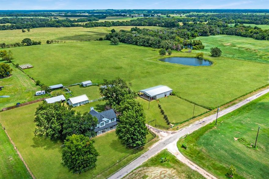 Welcome to your own slice of East Texas paradise, where space, functionality, and charm come together on 17.756 unrestricted acres. This beautifully designed two-story home offers 4 bedrooms and 2.5 baths, with a thoughtfully laid-out floor plan that places the spacious primary suite on the main level for comfort and convenience. The heart of the home is a large kitchen featuring real wood cabinetry, granite countertops throughout, and an oversized island perfect for gathering, along with a cozy eat-in breakfast area and a formal dining room for hosting. The living room makes a statement with soaring ceilings and expansive windows that perfectly frame a stunning wood-burning fireplace, creating a warm and inviting atmosphere. The primary suite is a true retreat with a spa-like ensuite bath that includes a soaking tub and separate his-and-her closets. A conveniently located half bath sits just off the laundry room with easy access to the outdoors, ideal for country living. Upstairs, you’ll find three additional bedrooms, a full bath, and a versatile game room or second living area that offers plenty of space for relaxation or entertainment. Step outside and experience everything this property has to offer for both recreation and functionality. The impressive 40x60 horse barn is equipped with five Priefert stalls, a wash station, turn-out pens, a tack room, and even a kitchenette area, making it perfectly suited for equestrian enthusiasts. The land is cross-fenced and includes a loafing shed, chicken coop, and both large and small storage buildings to accommodate all your needs. A spring-fed pond provides a peaceful setting for fishing, while the storm shelter offers added peace of mind. With ample road frontage and no restrictions, this property presents endless opportunities whether you’re looking for a working ranch, recreational retreat, or private homestead.