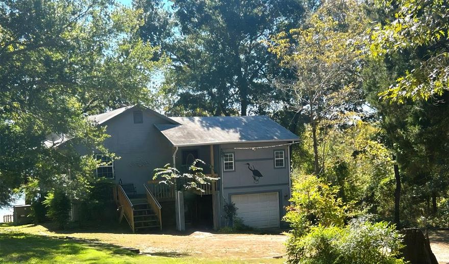 Serene 2-Bedroom Waterfront Home with Elevator & Workshop! Tucked away at the end of a quiet road in Christopher Ridge, this 2-bed, 2-bath  waterfront home offers peaceful lake living with over 50 ft. of waterfront, beautiful views, and easy water access—ideal for adding your own boat dock. Surrounded by mature trees, it features two living rooms, a dining area, and two en-suite bedrooms for comfort and privacy. The kitchen includes a gas stove, generous counter and cabinet space, and flows into the living areas. Enjoy the screened-in porch, open-air deck, and fenced backyard overlooking the lake. The elevator—conveniently accessed from the main living area— adds ease for all ages. Extras include a workshop in the one-car garage, ample parking, and nearby green space. Perfect for full-time living or weekend getaways!