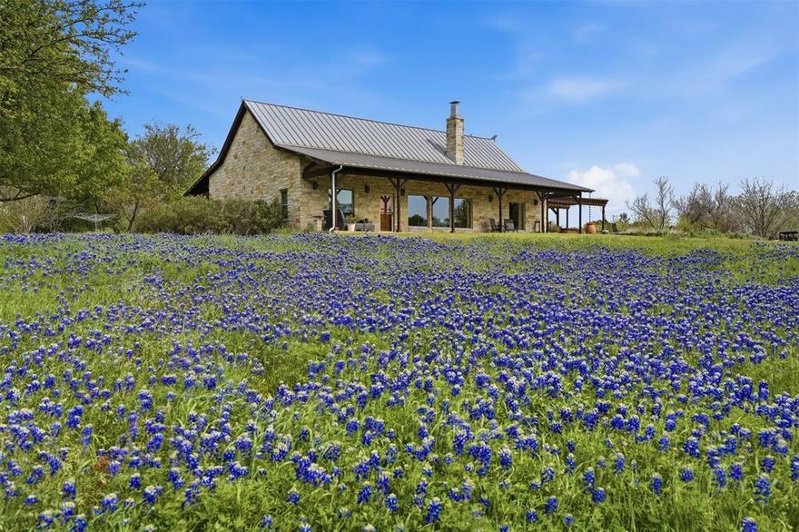 Nestled along a breathtaking stretch of the Brazos River, this extraordinary 83.8-acre estate offers a rare combination of natural beauty, privacy, and sustainable living. With approximately 1,377 linear feet of accessible river frontage, you can walk directly to the water’s edge and enjoy one of Texas’ most iconic rivers in a peaceful, secluded setting. The land is a stunning blend of majestic oak groves and open native pasture, ideal for recreation, wildlife, or agricultural use. A seasonal creek winds through the property, complete with a picturesque waterfall after rainfall, adding even more charm to this remarkable landscape. Overlooking the river sits a beautifully designed 3-bedroom, 2-bathroom home featuring a spacious open floor plan with soaring vaulted ceilings and abundant natural light. Both the living room and primary suite enjoy tranquil Brazos River views, creating a serene atmosphere throughout the home. The primary bathroom features heated floors and private access to the outdoor hot tub, offering a spa-like retreat. Expansive 10-foot porches on both sides of the home provide the perfect place to relax and take in the scenery. A commercial grade misting system along the porches allows for you to cool down on those hot Texas summer days. Designed with sustainability in mind, the property includes a fully operational 20,000-gallon rainwater catchment system with reverse osmosis and purification, a water well, and a stand-alone owned solar field. Additional improvements include a 60×40 shop, a pecan orchard with 49 trees, 10 fruit trees, plus a year-round garden and greenhouse. This exceptional Brazos River property truly feels like a private paradise and offers an incredible opportunity for a peaceful retreat, ranch, or self-sufficient homestead lifestyle.