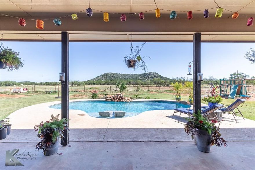 Experience country living with modern luxury in this stunning custom-built 4-bedroom, 2.5-bath home on 15 acres in highly sought-after Jim Ned ISD. This beautifully designed property offers a split bedroom floor plan and an open-concept living area featuring a cozy wood-burning fireplace and expansive windows along the back of the home, showcasing amazing countryside views and flooding the space with natural light. The home boasts granite countertops throughout, a spacious kitchen perfect for entertaining, and a luxurious primary suite with a sitting area, dual sinks, soaking tub, tiled shower, and a large wrap-around walk-in closet. The laundry room includes a mudroom area, sink, and extra storage for added functionality.
Outside, enjoy your private retreat with an in-ground gunite pool, waterfall feature, and sun deck. Additional features include a brand new roof, two-car garage, sprinkler system, and a perimeter fenced and cross-fenced property with an electric entry gate, ideal for privacy and livestock management.
Bring your animals—this property includes a show barn with additional storage, perfect for 4H projects, livestock, or hobbies. This one-of-a-kind property offers the perfect blend of space, comfort, and rural charm—all with modern amenities.